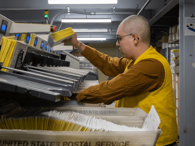 Staff members at the San Bernardino Registrar of Voters organize sealed ballot envelopes into a high speed electronic sorting machine that will capture the barcodes and signatures.