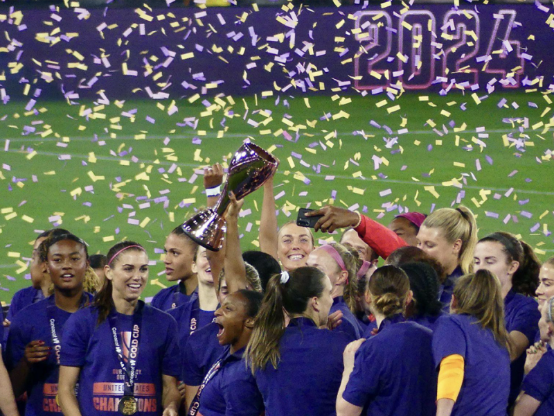 US defender Crystal Dunn raises the inaugural Gold Cup trophy after team USA defeated Brazil 1-0 at Snap Dragon Field.